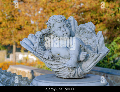 Fienile statua di un angelo in un parco d'autunno in un caldo pomeriggio contro uno sfondo di foglie di giallo, close-up Foto Stock