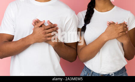 Tipo ragazzo e ragazza mantenendo le palme sul petto, essere grati Foto Stock