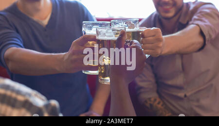 Immagine ritagliata di compagni tintinnanti bicchieri da birra Foto Stock