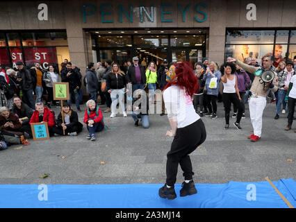 Manifestanti eseguire un 'fashion show' fuori Penneys su O'Connell street a Dublino durante una ribellione di estinzione (XR) dimostrazione, come i rivenditori di moda sono venuti sotto intenso scrutinio nell ultimo anno da attivisti ambientali. Foto Stock