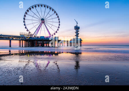 Colorato Tramonto sul litorale, spiaggia, pier e ruota panoramica Ferris, Scheveningen, l'Aia. Una lunga esposizione tecnica utilizzata. Foto Stock