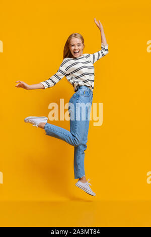 Teen girl divertendosi, saltando su arancione di sfondo per studio Foto Stock