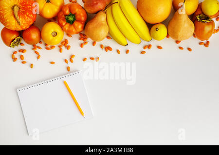 Autunno fresco giallo e arancione di frutta e verdura e notebook isolati su sfondo bianco, vista dall'alto. piatto. laici autunno sfondo. Foto Stock