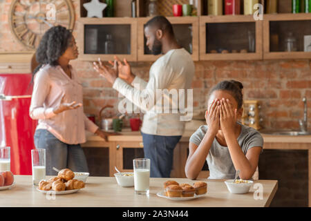 Ragazza Litttle gridando in cucina come genitori combattimenti Foto Stock