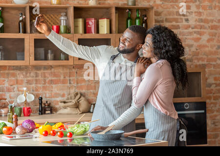 Felicemente sposata giovane tenendo selfie sullo smartphone in cucina Foto Stock