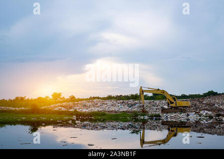 Un retroescavatore giallo è il sollevamento di garbage a separazione dei rifiuti vegetali, Montagna grande mucchio di rifiuti e inquinamento,pila di puzzano e residuo tossico,Questi garbage Foto Stock