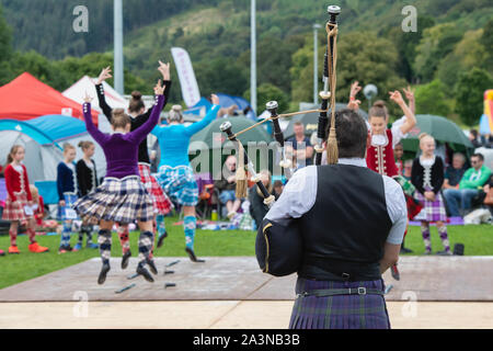 Piper e highland dancing ragazze a Peebles Highland Games. Peebles, Scottish Borders, Scozia Foto Stock