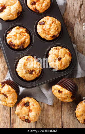 Muffin con pomodori secchi e formaggio cheddar close-up in una teglia sul tavolo. Verticale in alto vista da sopra Foto Stock