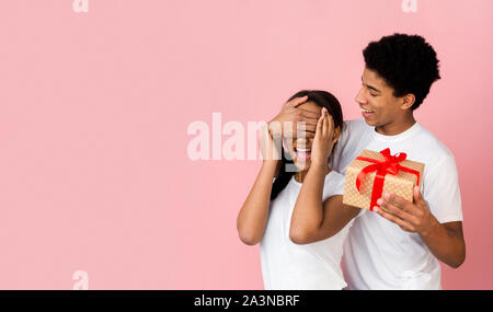 Teen guy preparazione regalo per ragazza, chiudendo gli occhi Foto Stock