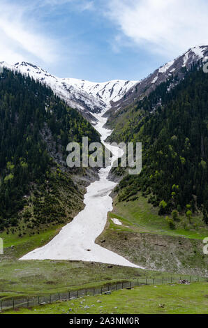 Un fiume congelato da oltre un nevato picco di montagna si vede in Baltal, Jammu e Kashmir India Foto Stock