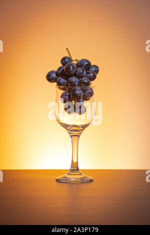 Idea concettuale delle uve in vino vetro come materia prima al posto del prodotto finale Foto Stock