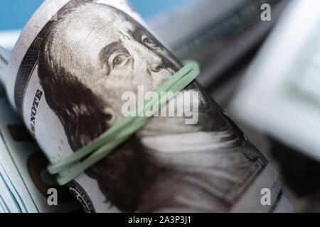 Close up macro di carta moneta rotolo di cento dollari lavorato a maglia con fascia di gomma Foto Stock