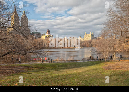 Il parco centrale, la vista della luce del giorno di New York con le persone che camminano, lo skyline di New York, il riflesso in acqua, le nuvole e gli alberi Foto Stock