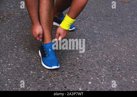 Giovane maschio conciate runner lacci delle scarpe di legatura, ottenere pronto per una corsa. Il concetto di uno stile di vita sano, la libertà. Foto Stock