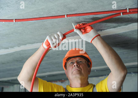 L'elettricista è fissare un elettrico tubo corrugato al soffitto. Foto Stock