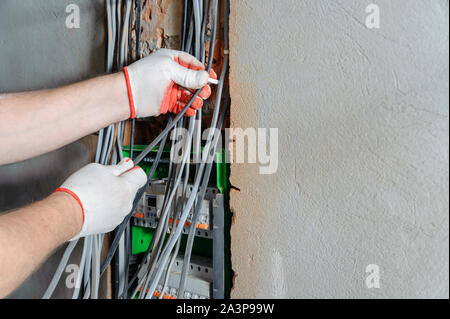 Un elettricista è l'installazione di cavi elettrici in una commutazione scatola dei fusibili. Foto Stock