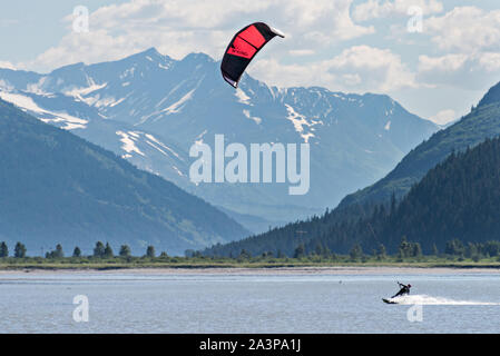 Un kite surfer passa di montagne innevate su 20 miglia di fiume vicino a Portage, Alaska. Foto Stock