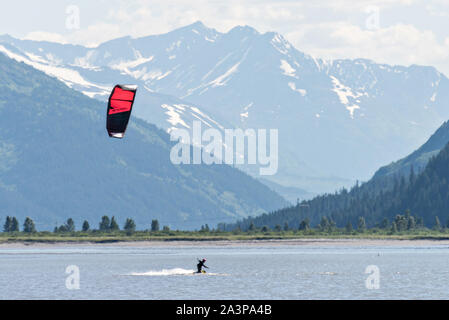 Un kite surfer passa di montagne innevate su 20 miglia di fiume vicino a Portage, Alaska. Foto Stock