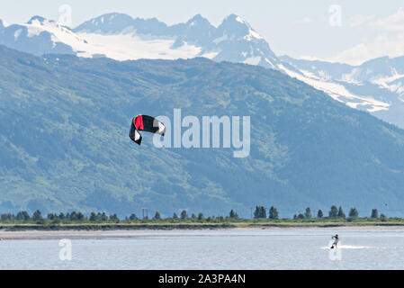 Un kite surfer passa di montagne innevate su 20 miglia di fiume vicino a Portage, Alaska. Foto Stock