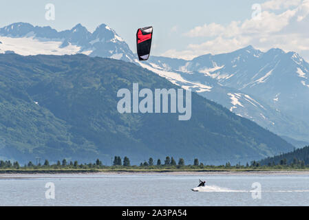 Un kite surfer passa di montagne innevate su 20 miglia di fiume vicino a Portage, Alaska. Foto Stock