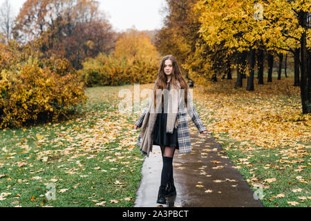 Red-headed freckled ricci ragazza in Giallo autunno park. La prima neve, pioggia umido Foto Stock