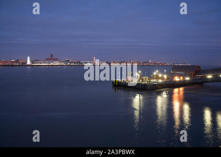 Woodside ferry terminal in Birkenhead illuminata di notte, con il Liverpool skyline della città attraverso il fiume Mersey Foto Stock