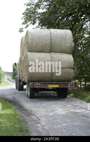 Rimorchio per trattore trasportanti grandi balle di fieno su strette strade di campagna Lane Foto Stock