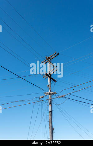 Molte linee di alimentazione e i cavi compresi alta tensione di distribuzione collegare sulla cima di un PG&E il polo di alimentazione (polo telefonico) contro il cielo blu, il Bay Area, California Foto Stock