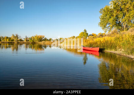 Rosso canoa in tandem con un dispositivo di compressione su di un lago calmo shore, inizio scenario autunnale Foto Stock