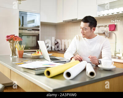 Giovani asiatici free lance designer seduti al bancone cucina creando un progetto utilizzando la pen tablet e computer laptop. Foto Stock