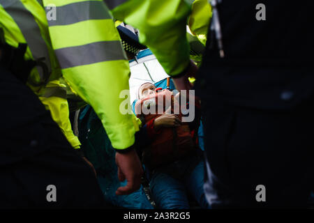 Gli ufficiali di polizia prepararsi ad arrestare un membro del cambiamento climatico movimento attivista ribellione di estinzione (XR) rifiuta di passare da un accampamento su Victoria Street durante il terzo giorno del gruppo 'International Rebellion' a Londra.gli ufficiali di polizia continuano a cancellare i dimostranti e tende dai siti in Westminster, con attivisti che è stato messo in guardia circa il passaggio a una protesta designata area attorno a Nelson la colonna in Trafalgar Square o arresto volto. Blocchi simili dalla ribellione di estinzione in aprile, in corrispondenza di siti quali Oxford Circus e Waterloo Bridge, visto più di mille arrestati, una TAC Foto Stock