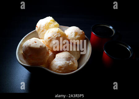 Brasiliano Ciambelle col formaggio. Pane al formaggio. Pao de Queijo e caffè. Sfondo scuro in stile d'arte. Tasto basso fotografia. Foto Stock