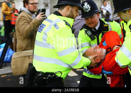 La polizia facendo molta attenzione a proteggere la testa di un'estinzione della ribellione protestor durante l'esecuzione del mandato di cattura il 8 ottobre 2019. Estinzione della ribellione arrestare strade di Londra. Londra centrale chiuso da demo. Foto Stock