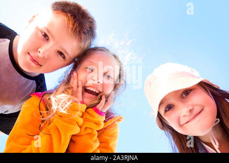 Gruppo di tre felice, sorpreso i bambini guardando giù al visualizzatore. Foto Stock