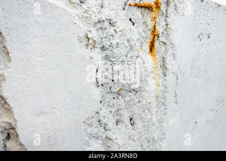 Un bianco muro di pietra con rusty bit di rebar sporgente. Foto Stock