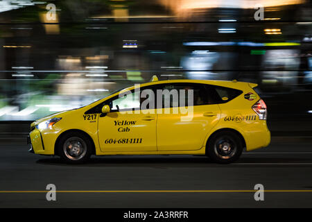 VANCOUVER, BC, Canada - Settembre 21, 2019: a Vancouver Yellow taxi accelerando verso West Georgia Street su un occupato Sabato notte. Foto Stock