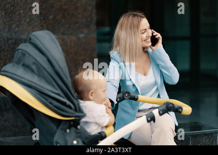 Ritratto di una donna d'affari di successo in tuta blu con il bambino. Business donna parla al telefono Foto Stock