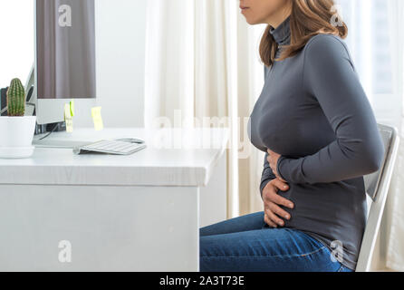 Dolore addominale di una donna durante il lavoro. Foto Stock