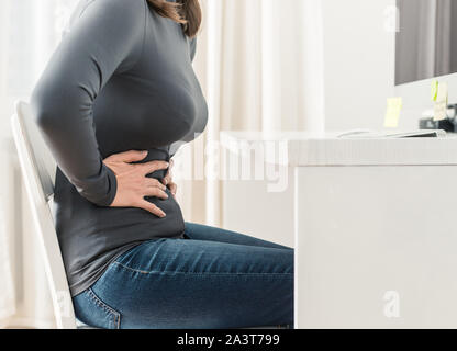 Dolore addominale di una donna durante il lavoro. Foto Stock