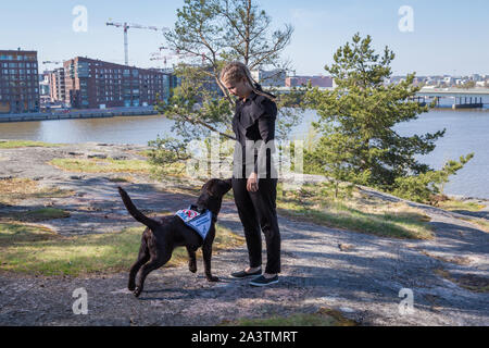 Giovane donna alla formazione un labrador retriever cane guida all'aperto Foto Stock