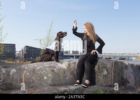 Giovane donna alla formazione un labrador retriever cane guida all'aperto Foto Stock