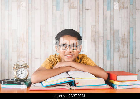 Giovani asiatici attraente studente maschio sorridere mentre guardando la telecamera seduto contro la tabella con i libri. Concetto di istruzione, felice studente e expressi Foto Stock