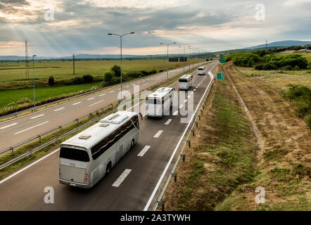 Roulotte o un convoglio di quattro autobus di linea che viaggiano su una autostrada Autostrada del paese Foto Stock