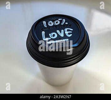 Monouso di tazza di caffè con una mano un messaggio scritto del 100% l'amore. Molto pulito l'immagine. Stilizzato. Foto Stock
