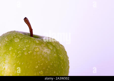 Verde mela con gocce d'acqua su bianco Foto Stock