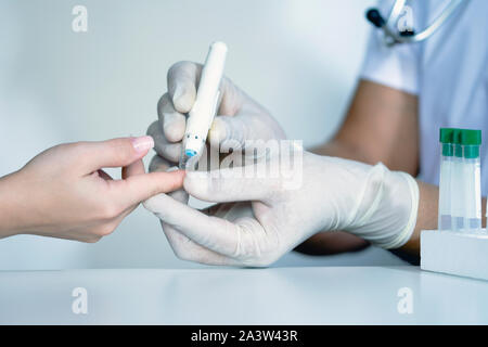 Medico controllo livello di zucchero nel sangue, medico utilizzando lancelet sul dito, verifica il livello di glucosio nel sangue Foto Stock