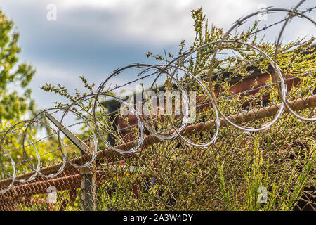 Filo di rasoio sul vecchio arrugginito catena collegamento recinto Foto Stock