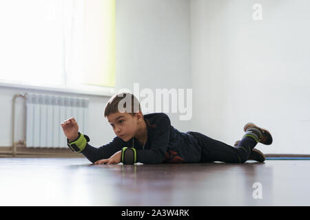 Little Boy giacente su stomaco durante la fisioterapia. Fare alcuni exersice, presentano alcuni problemi di salute. Foto Stock