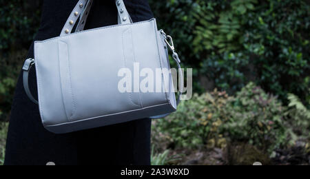In pelle grigio donne texture borsa su azienda femmina, moda mockup in fondo naturale Foto Stock