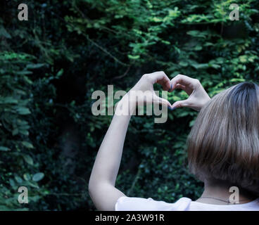 Mani femminili forma di cuore sulla natura isolata sullo sfondo Foto Stock